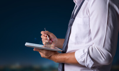 Close-up of a professional man in a tie using a stylus on a tablet, analyzing graphs and financial...