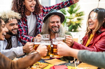 Young friends diversity age drinking and toasting beer pints glasses at brewery bar garden out side...