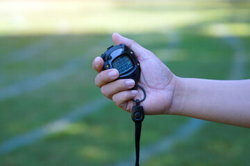 coach timed the finish line with a stopwatch to determine the winner of the school sports day running event. soft and selective focus.