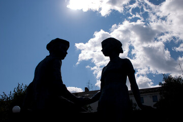 Silhouette of a man and a woman sitting on a bench