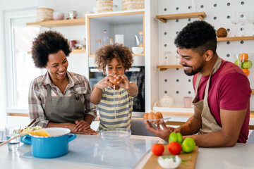 Happy african american family preparing healthy food in kitchen, having fun together on weekend