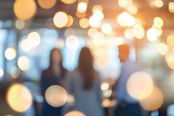 Blurred image of three people socializing in a brightly lit  bokeh filled interior.