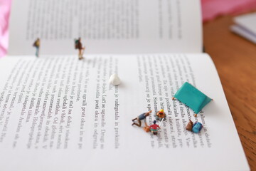 Miniature people. Father and son camping on a page of a book.