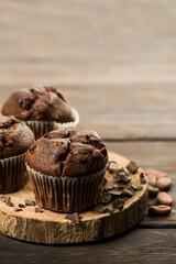 Chocolate chip muffins with chocolate on wooden table.