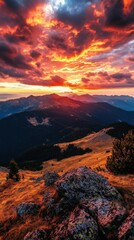 Obraz premium Breathtaking sunset over mountains with vibrant clouds and rocky foreground.