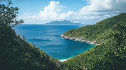 Fototapeta premium Secluded cove with turquoise water, lush green hills, and distant island under a blue sky.
