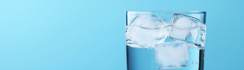 Obraz premium crystal clear glass tumbler filled with refreshing water and ice cubes, set against vibrant blue background, evokes sense of coolness and hydration