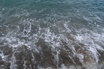 Water sea beach. Wave ocean blue. Stone texture reflection sun. Surface coast pebbles. 