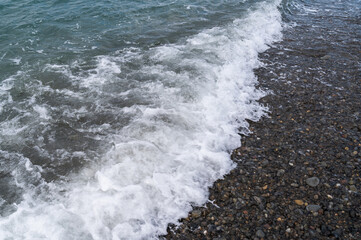 Water sea beach. Wave ocean blue. Stone texture reflection sun. Surface coast pebbles. 