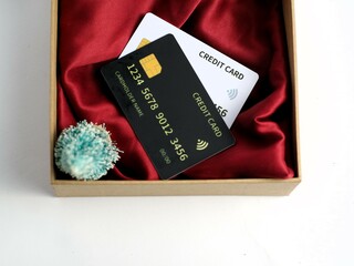 Credit card showcased on red cloth base in a minimalist opened cardboard  gift box, isolated...
