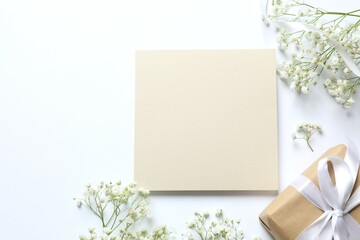 Top view photo with paper card, gift box and gypsophila flowers on white background with empty space