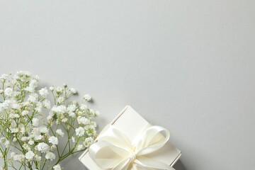 Top view photo with gift box and gypsophila flowers on gray background with empty space