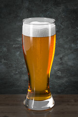 Glass with beer on wooden table against the wall in grunge style. Bar theme.  Dark environment. 3d rendering.