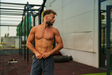 Obraz premium Shirtless man with a muscular build standing in outdoor gym.