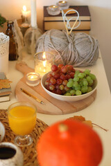 Pumpkins, various food and drinks, fall decorations, books and candles on the table. Fall hygge at home. Selective focus.