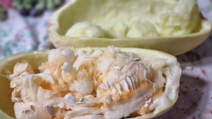 A zucchini split open, revealing its seeds and inner pulp on a patterned surface