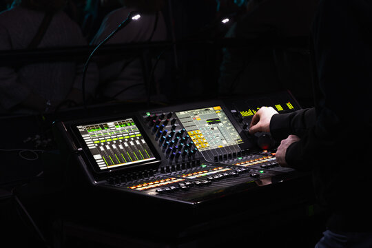 Hands of a sound engineer working at a mixing console, close-up