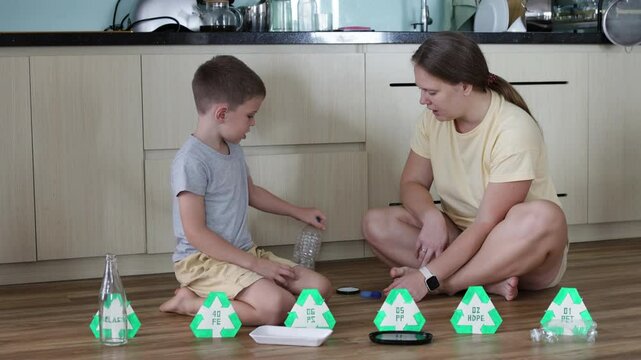 Mother and son work together at home sorting various types of waste.