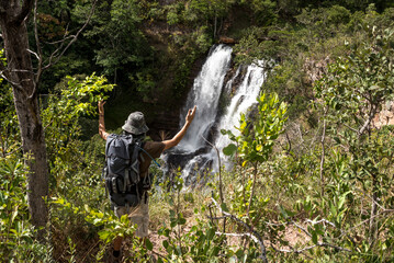 hiker with a backpack looking at a waterfall in the forest