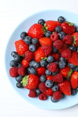 Different fresh ripe berries in bowl on the table
