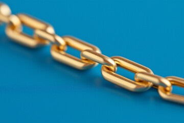 Obraz premium Close-up of a sleek gold chain on a vibrant blue background, showcasing luxury, strength, and elegance with ample copy space