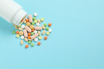 Various pills pouring out of medicine bottle on colorful background