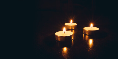 Three burning candles on a black background.