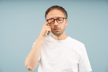 Fototapeta premium Eye problem. Tired man feels irritated rubbing dry eyelids for relief vision pain isolated studio. Male wearing eyeglasses suffer bad blurry vision by conjunctivitis, allergy, inflammation, infection