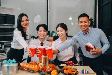 full length view of a group of business team wearing red Santa hat and exchange gift box together in the office for Christmas.