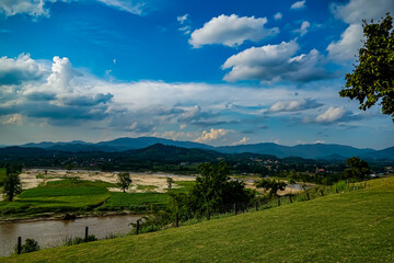 Fototapeta premium Scenic river landscape with rolling hills and dramatic clouds in a picturesque natural setting