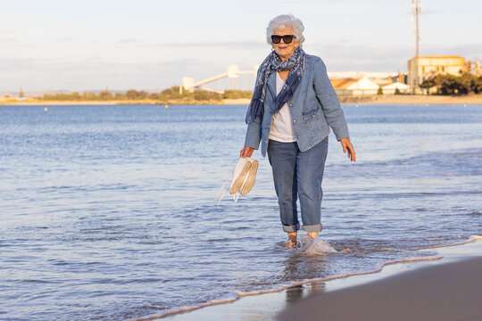 elderly lady getting her feet wet walking on beach at Koombana Bay