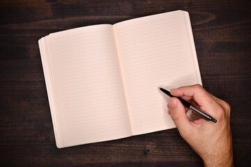 Hand writing with pencil into a blank diary as mockup copy space