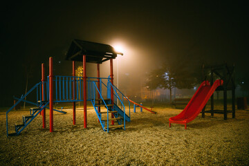 Empty playground at foggy winter night