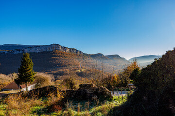 A serene autumn scene featuring golden trees and rocky cliffs under a clear blue sky in northern...