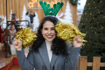 Cheerful woman playing with golden pom-poms during christmas time 