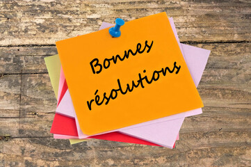 Papier en couleur punaisé sur d'autres papiers en couleur sur lequel est écrit bonnes résolutions