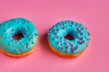 Three donuts with blue frosting on a pink background. A donut with a pink background and blue donuts. Blue donuts pink background sweetness lies. Pink donuts lying on a lifestyle background of pink.