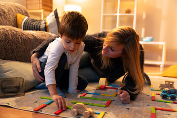 Mother and son building a road with colorful wooden blocks at home