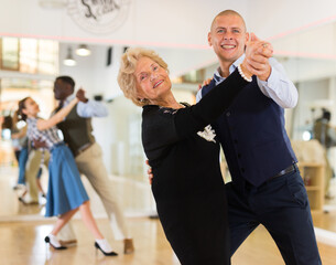 Elderly woman learning ballroom dancing movements in pair