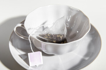 Pyramid tea bag in an empty tea pair. Porcelain cup and saucer