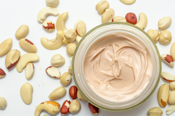 A jar of cream with nuts on a white surface. A jar of nuts with a white background. Nuts jar white background cosmetics cream. A jar of cream and nut cosmetics on a white lifestyle background.