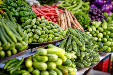 Close-up of a vegetable stall featuring cucumbers, bitter gourds, beans, and peppers, representing the freshness and richness of Indian farm produce.