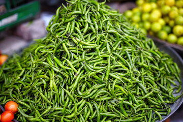 Close-up of a vibrant pile of fresh green chilies at an Indian market, showcasing their natural freshness and use in traditional Indian cuisine.