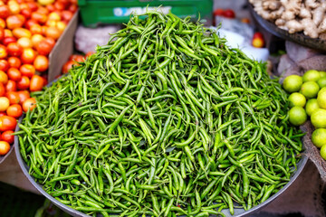 Close-up of a vibrant pile of fresh green chilies at an Indian market, showcasing their natural freshness and use in traditional Indian cuisine.