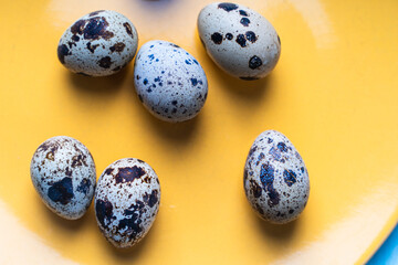 Obraz premium Quail eggs in shell on a yellow plate. The concept of a healthy breakfast.
