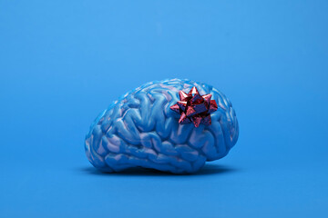 Blue brain with a gift bow on a plain blue background. Symbolizing 'Blue Monday' the saddest day of the year, with a hint of irony