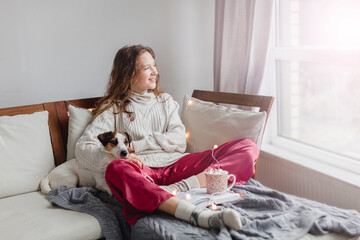 Young woman with dog drinking warm coffee at home
