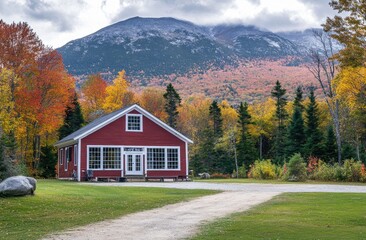 A red New England home in the White Mountains, with fall foliage and a mountain peak backdrop