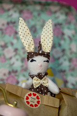 "Handmade: Cute textile toy in the shape of a bunny. Elegant design with a polka dot fabric pattern, decorated with a bow and pearl. The atmosphere of warmth and care, suitable for creativity, handmad