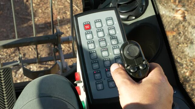 Unloading timber from a logging truck. Close-up of joystick control